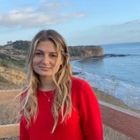 Hannah Foley in a red sweater beside the coast.